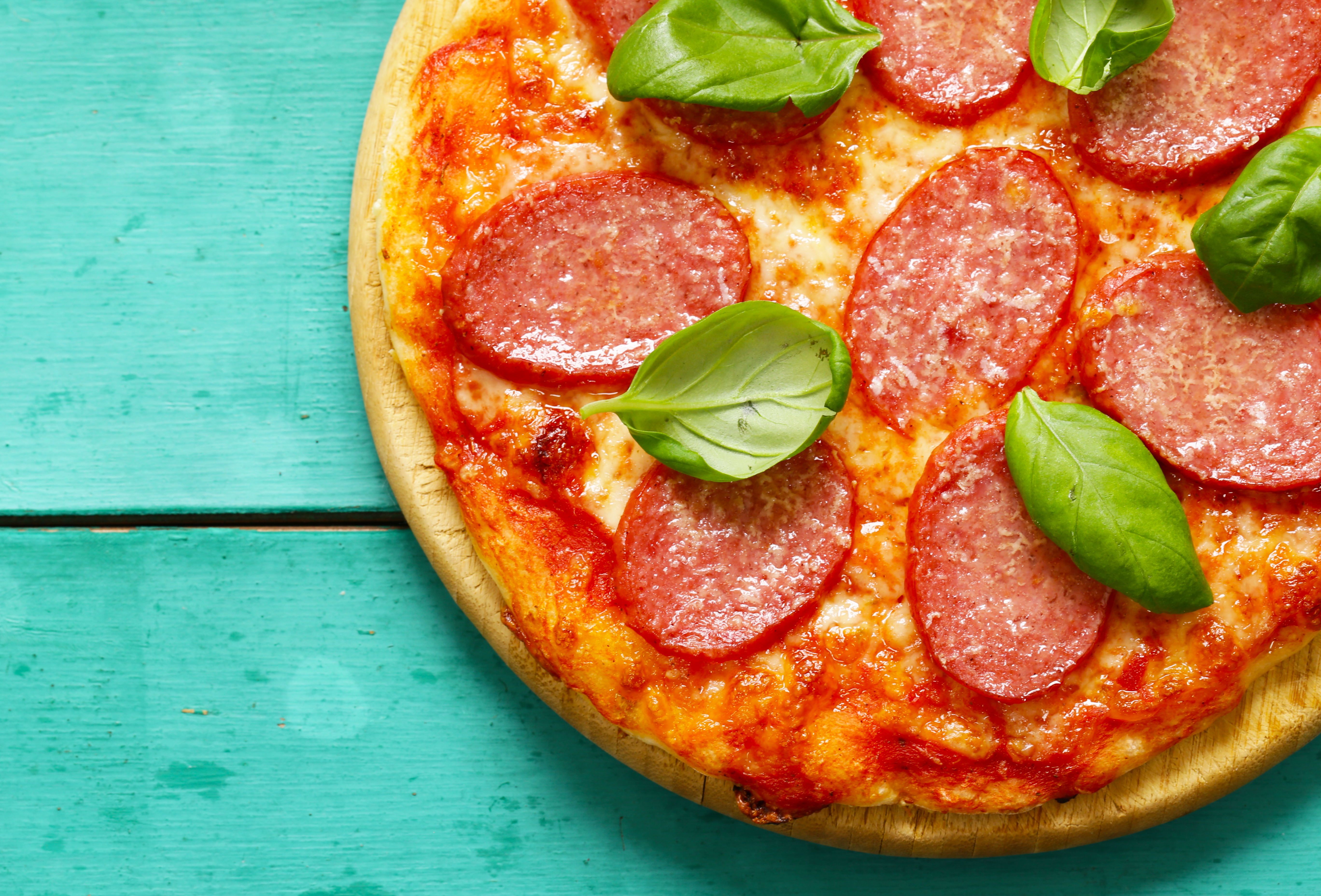 pepperoni pizza with fresh basil on a wooden background
